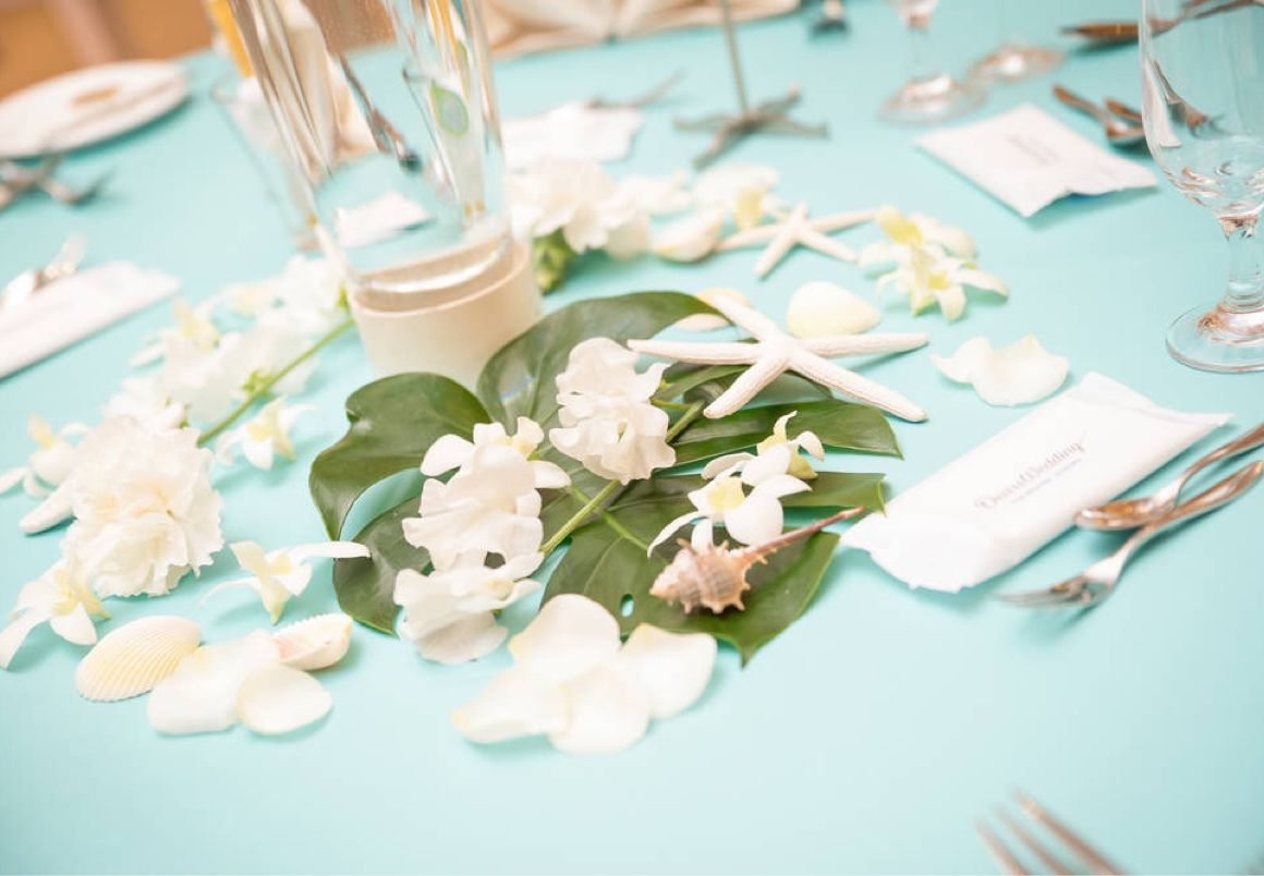 ティファニーブルーのテーブルクロスにモンステラと白いお花、貝殻を散りばめてマリン風に♪