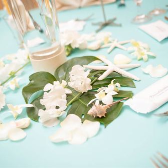 ティファニーブルーのテーブルクロスにモンステラと白いお花、貝殻を散りばめてマリン風に♪